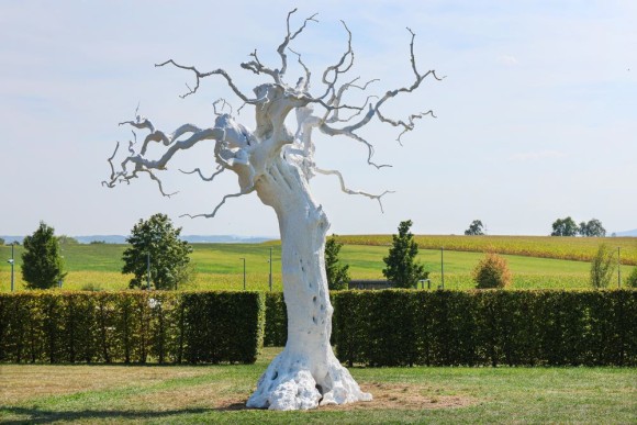 The image shows an installation shot of an sculpture by Ugo Rondinone. The artist placed a white tree sculpture in front of the Hohenlohe landscape. 